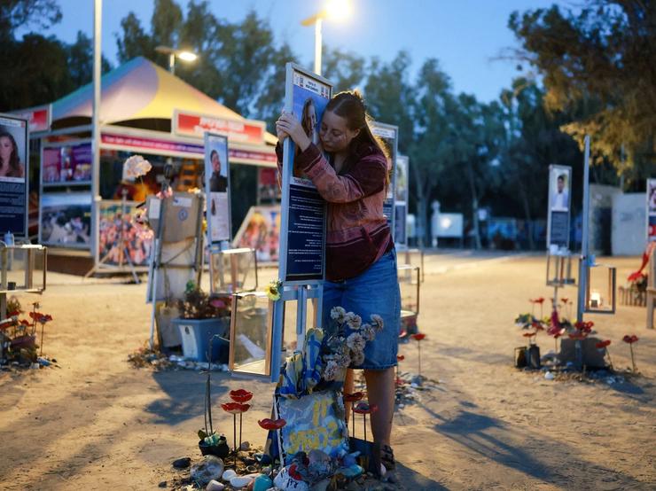 A woman hugs a sign at a memorial at the site of the Nova music festival