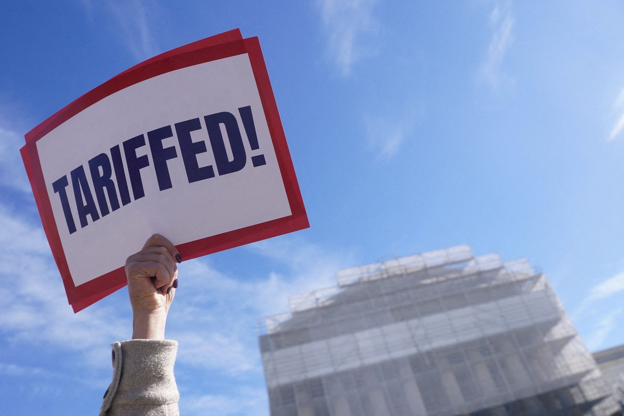 A protester holds a placard that says ‘Tariffed!’