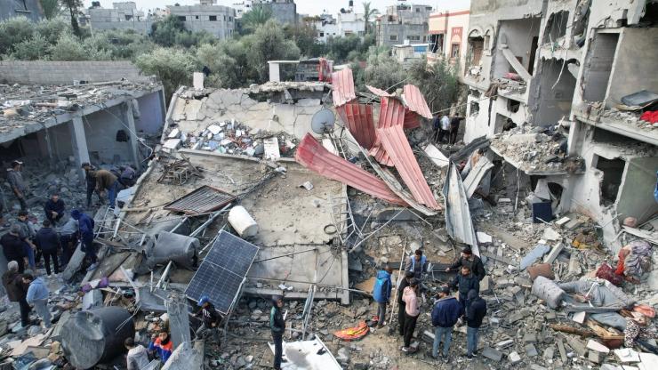 Palestinians gather at the site of Israeli strikes on houses, amid the ongoing conflict between Israel and the Palestinian Islamist group Hamas, at the Maghazi camp in the central Gaza Strip, December 25, 2023.