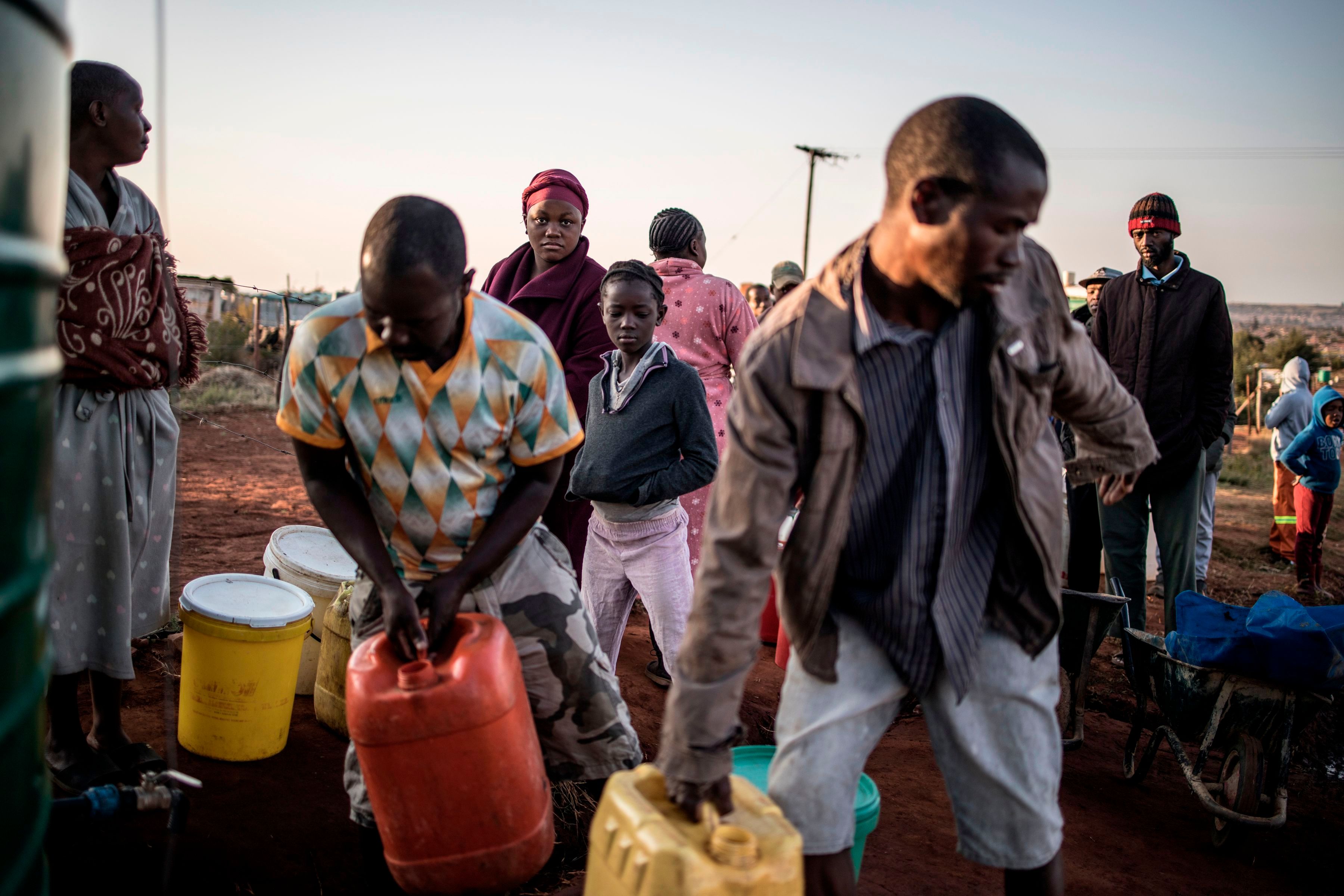 Residents of an informal settlement outside of Johannesburg carry water.