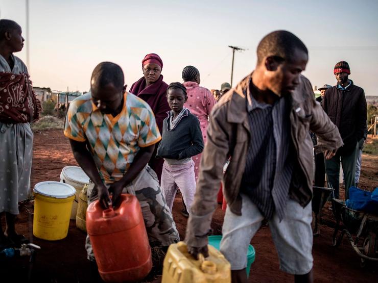 Residents of an informal settlement outside of Johannesburg carry water.