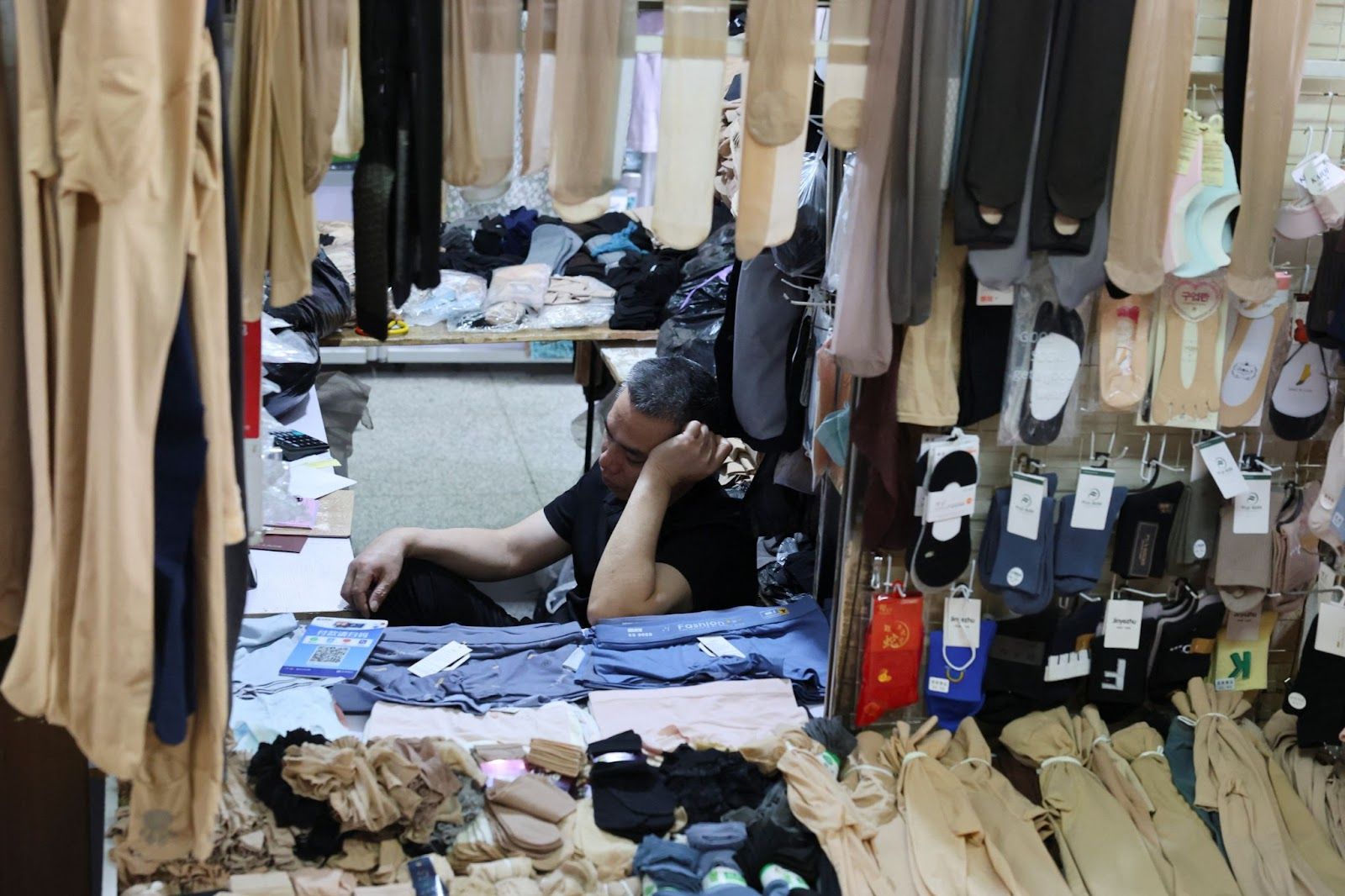 A worker sits in an garment store in Shanghai.