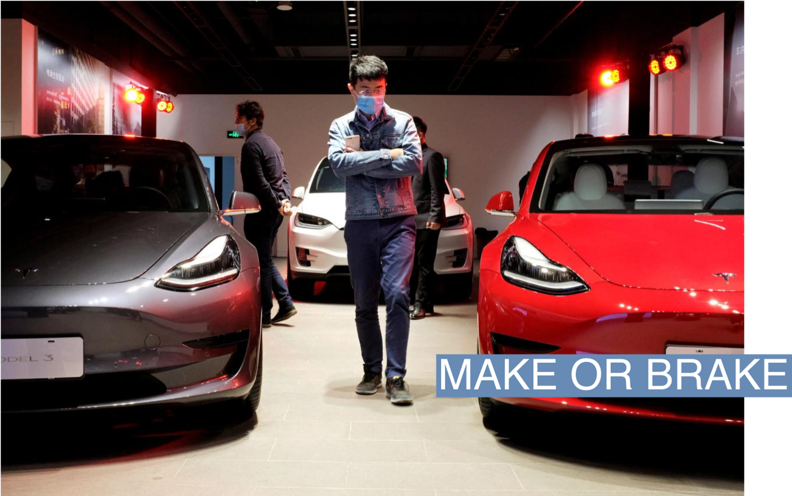 A man walks by Tesla Model 3 sedans and Tesla Model X sport utility vehicle at a new Tesla showroom in Shanghai, China May 8, 2020. 