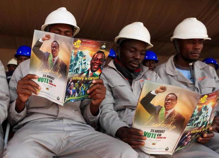 Workers read magazines with pictures of Zimbabwe’s President Emmerson Mnangagwa.