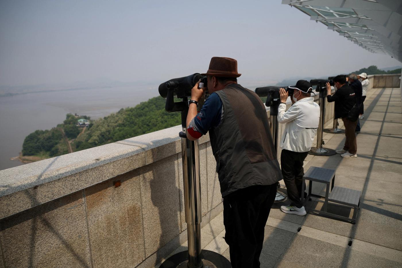 South Korean people look toward the North through binoculars at an observation post near the demilitarised zone separating two Koreas in Paju, South Korea, May 17, 2022. REUTERS/Kim Hong-Ji/File