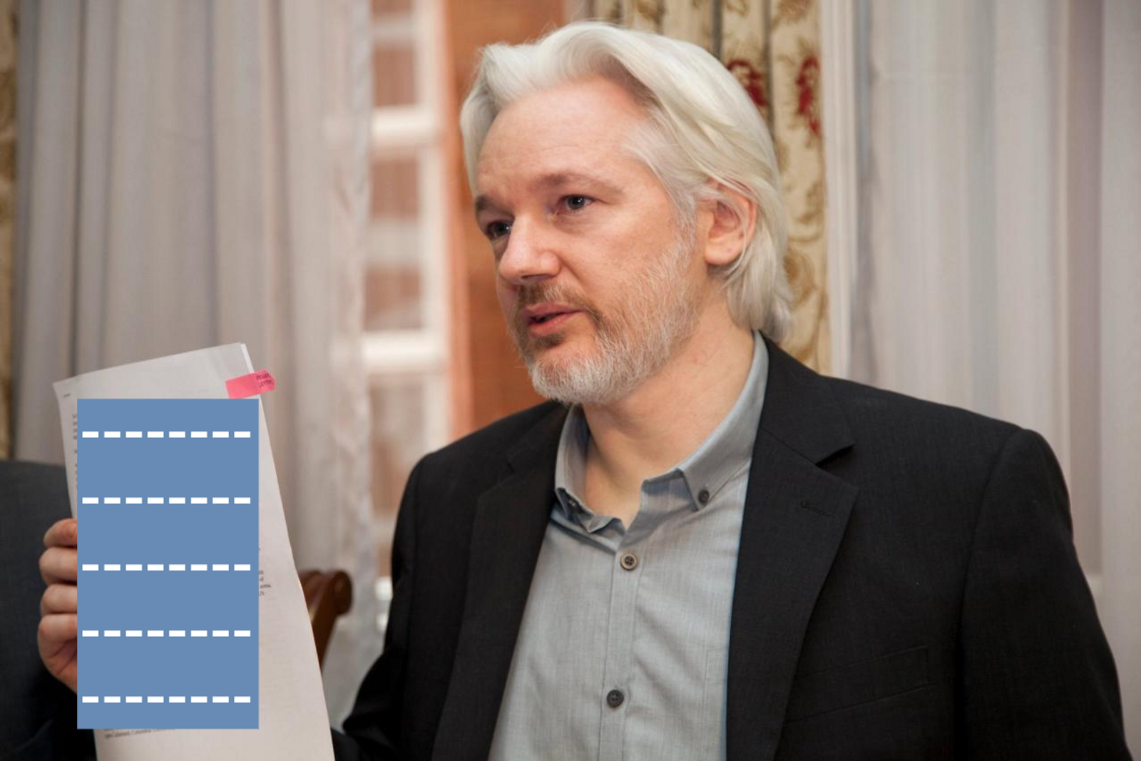 Julian Assange holds up a labeled document.
