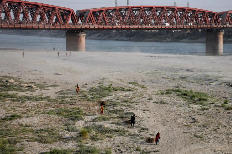 People walk on a dry riverbed of the Indus River in Pakistan.