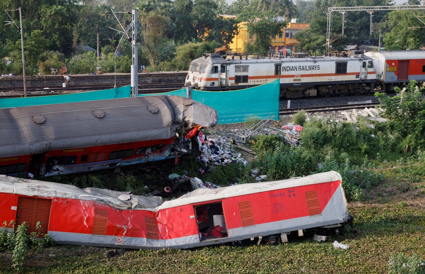 A train moves past damaged coaches, after the tracks were restored, at the site of a train collision following the accident.