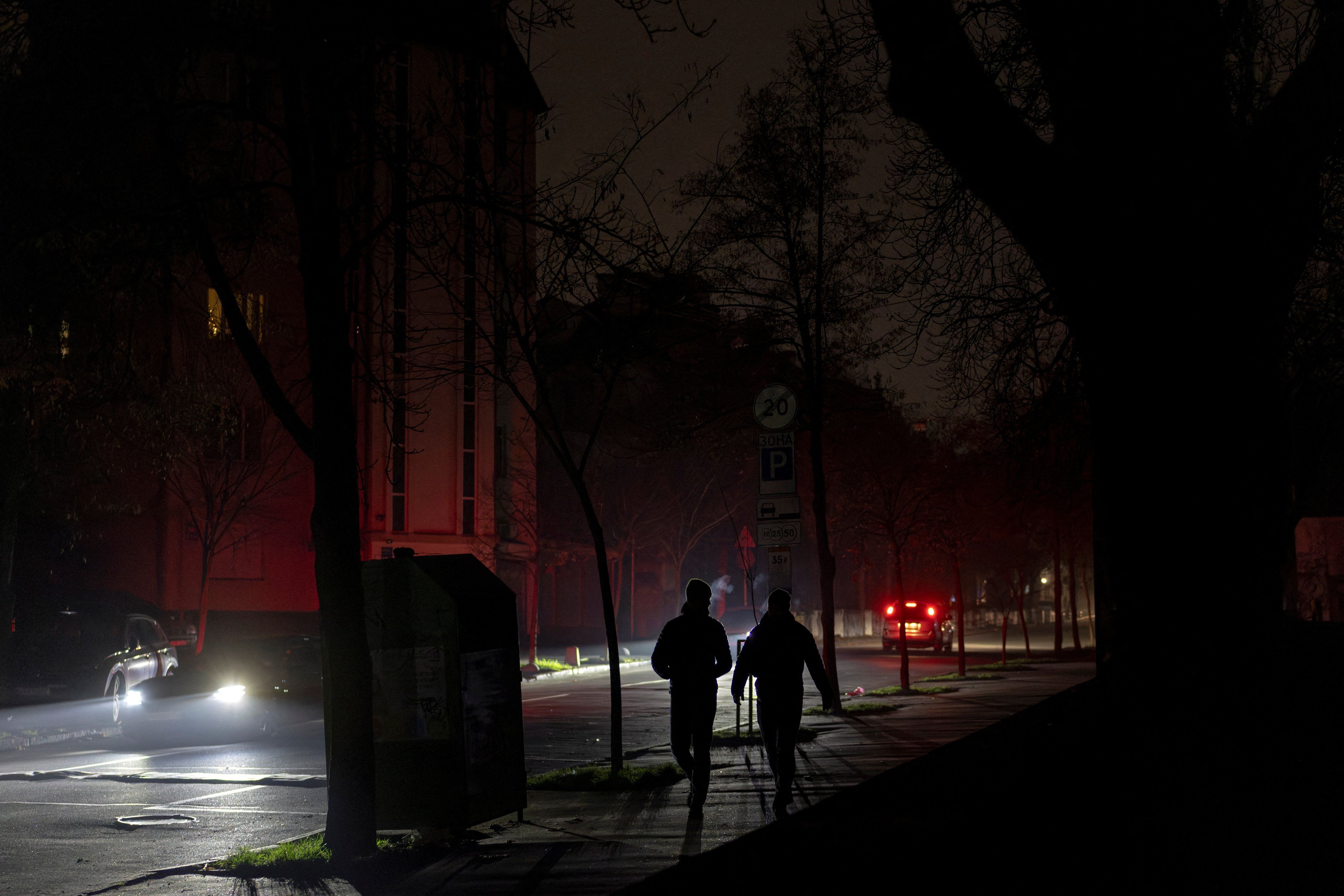 People walk in an unlit street in Kyiv. 