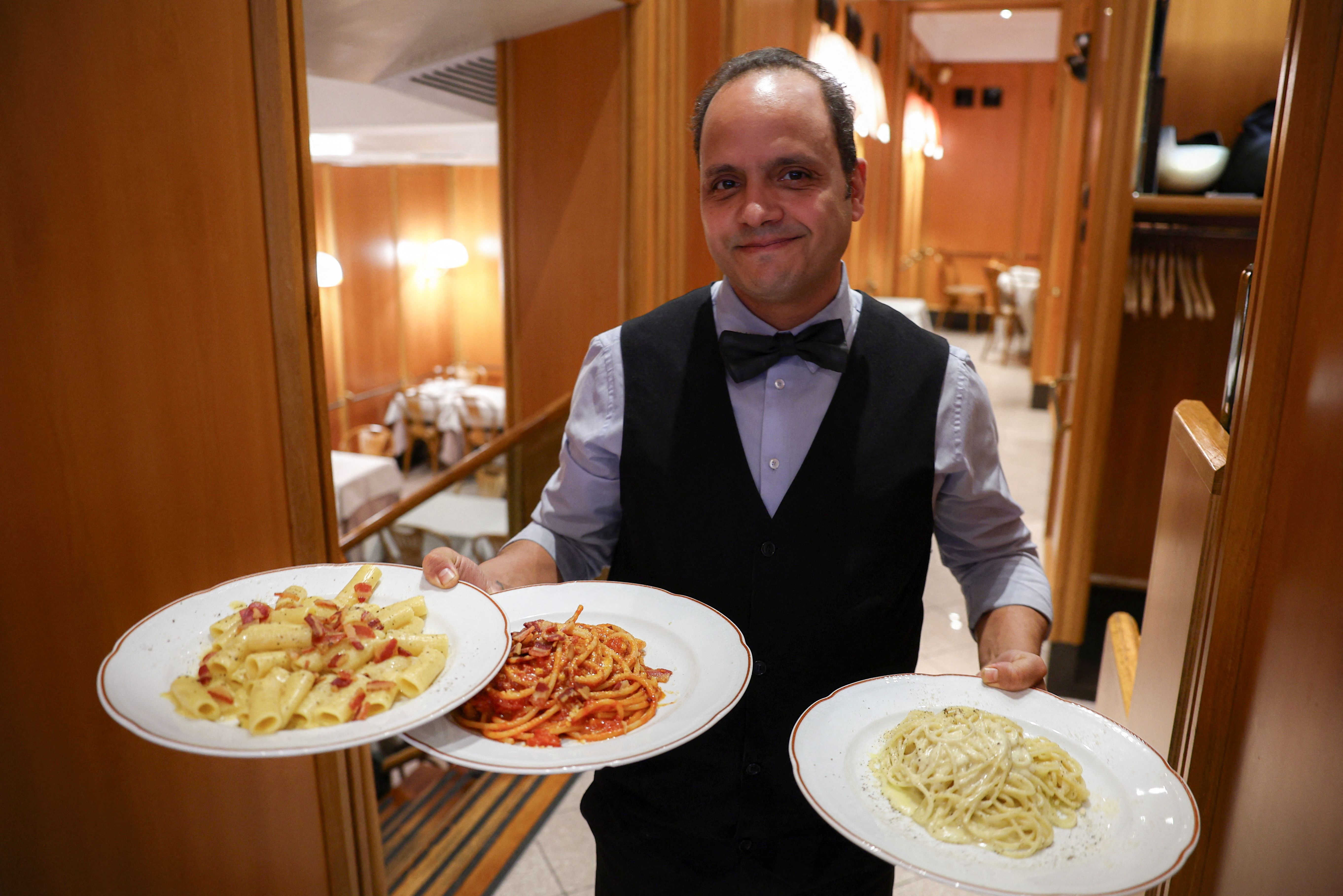 A waiter carrying pasta plates in Rome.