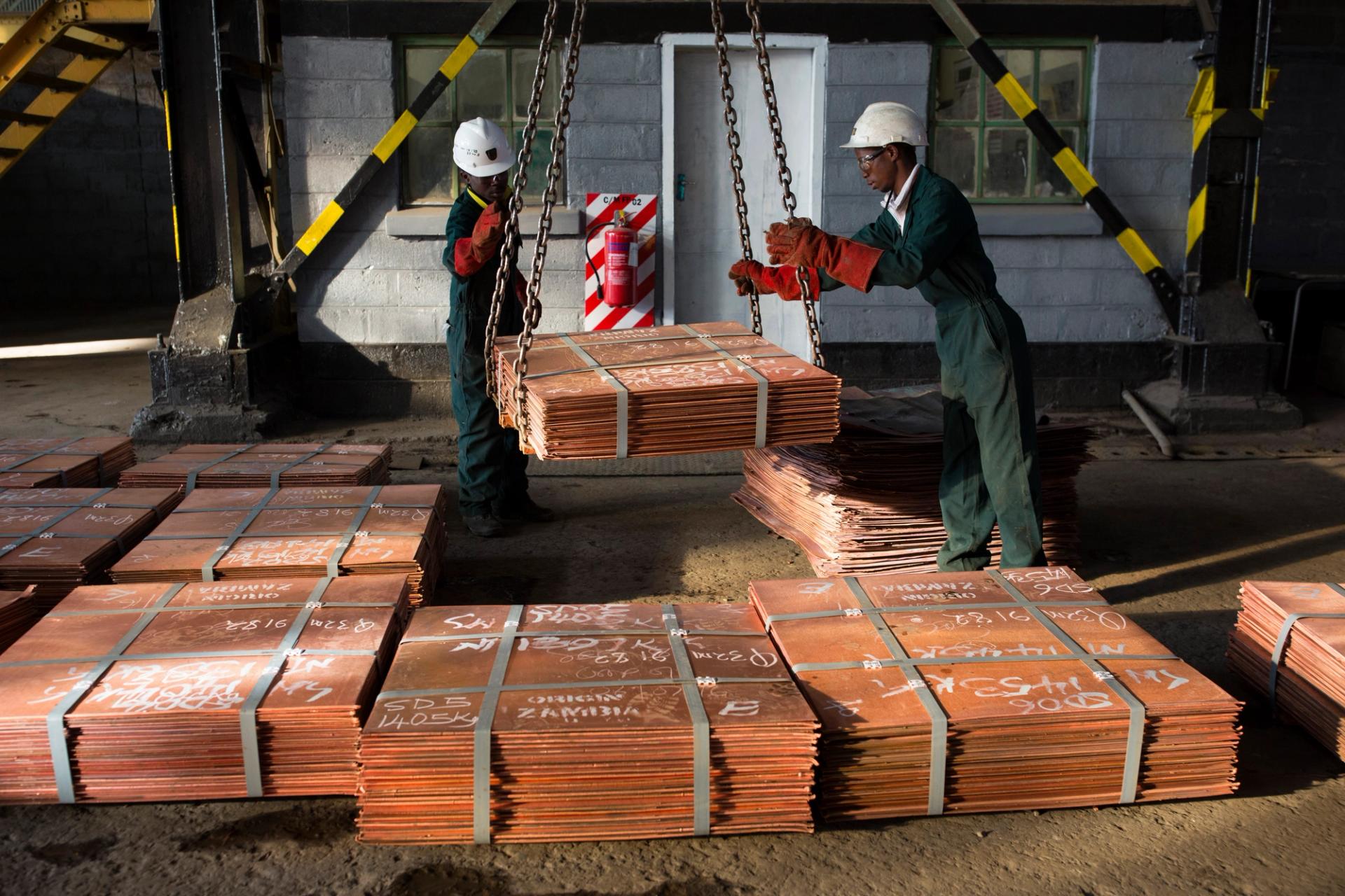 Workers move batches of copper sheets, which are stored in a warehouse and wait to be loaded on trucks in Mufulira, Zambia.