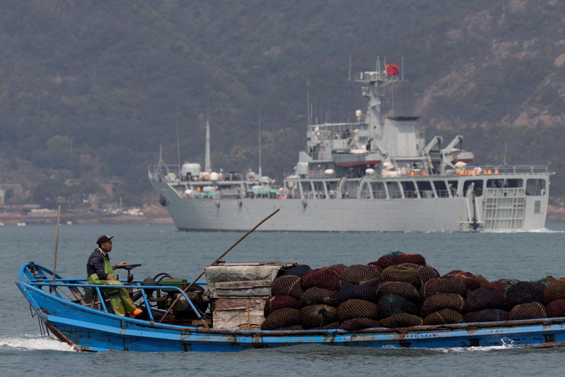 FILE PHOTO: A fishing boat sails past a Chinese warship during a military drill off the Chinese coast near Fuzhou, Fujian Province, across from the Taiwan-controlled Matsu Islands, China, April 11, 2023. REUTERS/Thomas Peter/File Photo