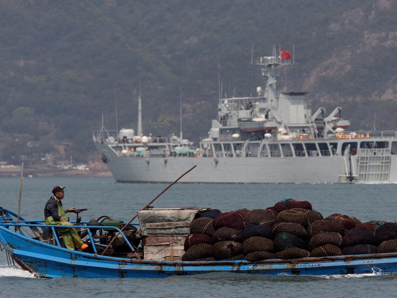 FILE PHOTO: A fishing boat sails past a Chinese warship during a military drill off the Chinese coast near Fuzhou, Fujian Province, across from the Taiwan-controlled Matsu Islands, China, April 11, 2023. REUTERS/Thomas Peter/File Photo