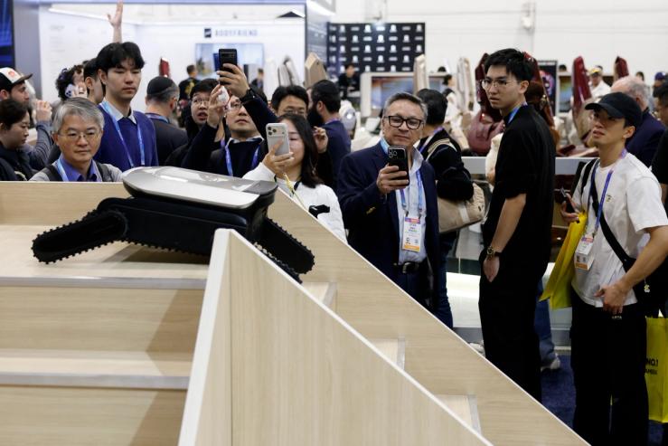 People watch as a Cyber X robot moves up and down stairs at a Dreame booth of the annual Consumer Electronics Show (CES) in Las Vegas