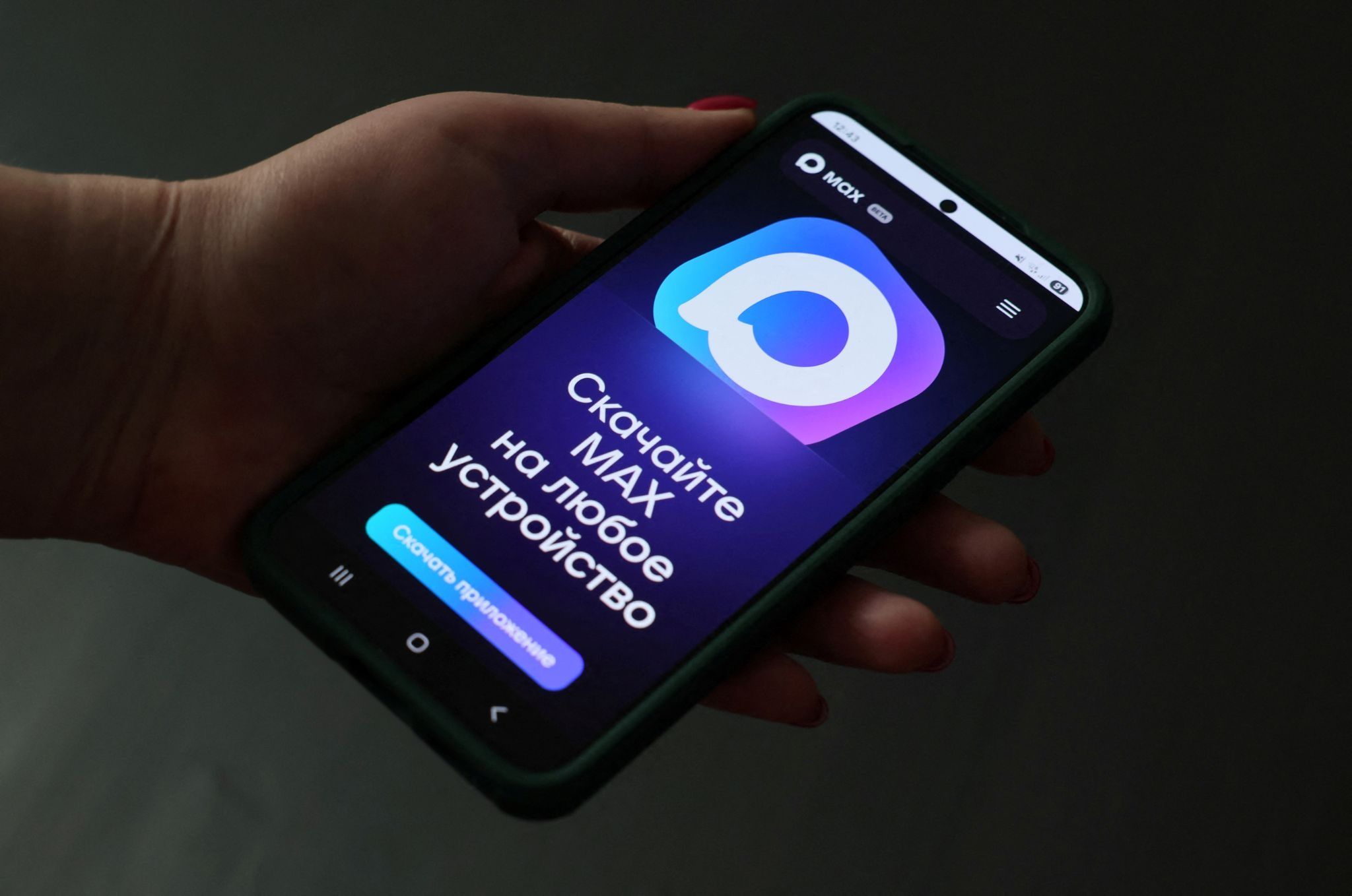A hand holding a phone displaying Russia’s MAX app