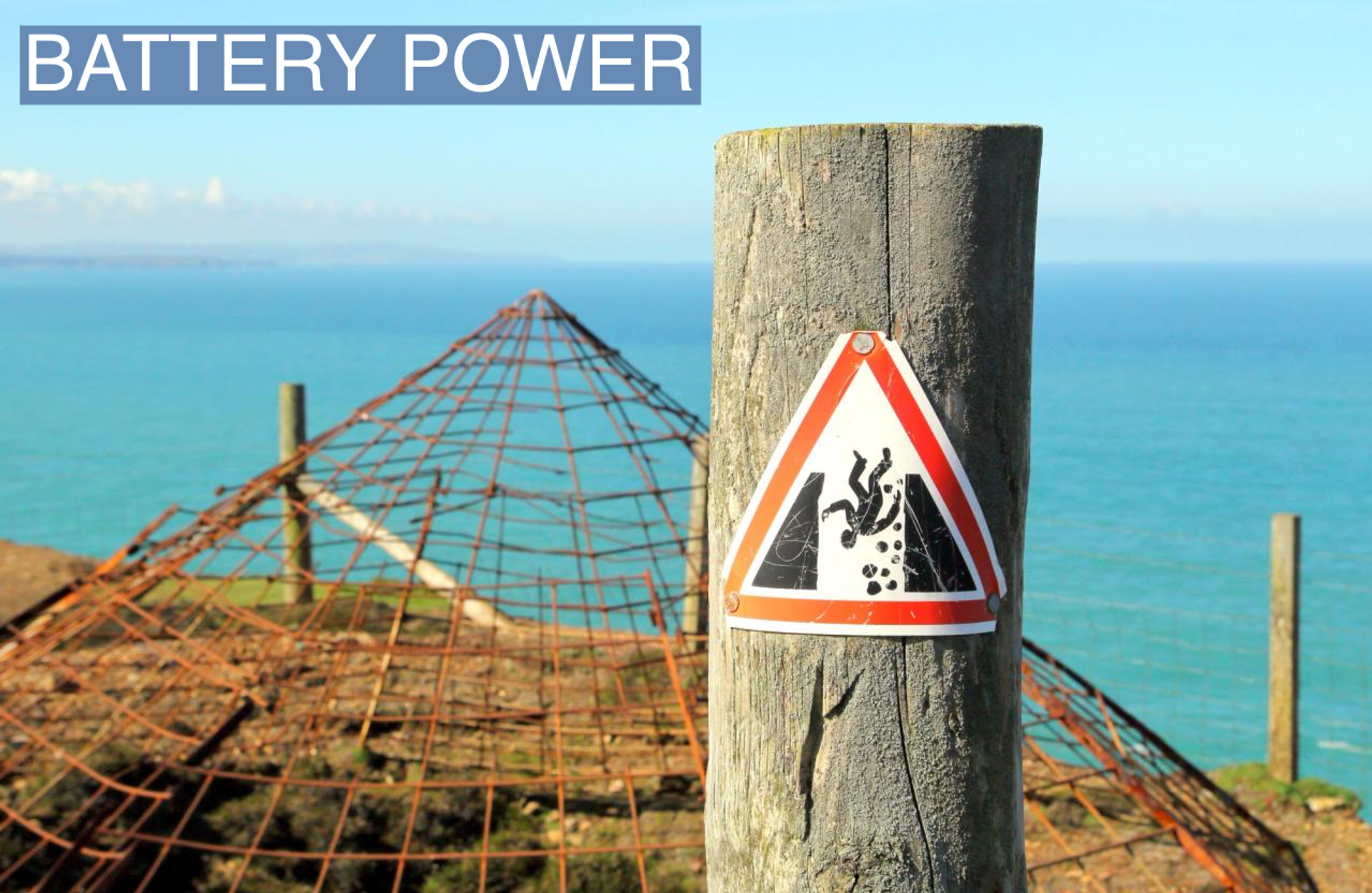 Warning sign indicating danger of falling, near the covered opening of a disused tin mine shaft