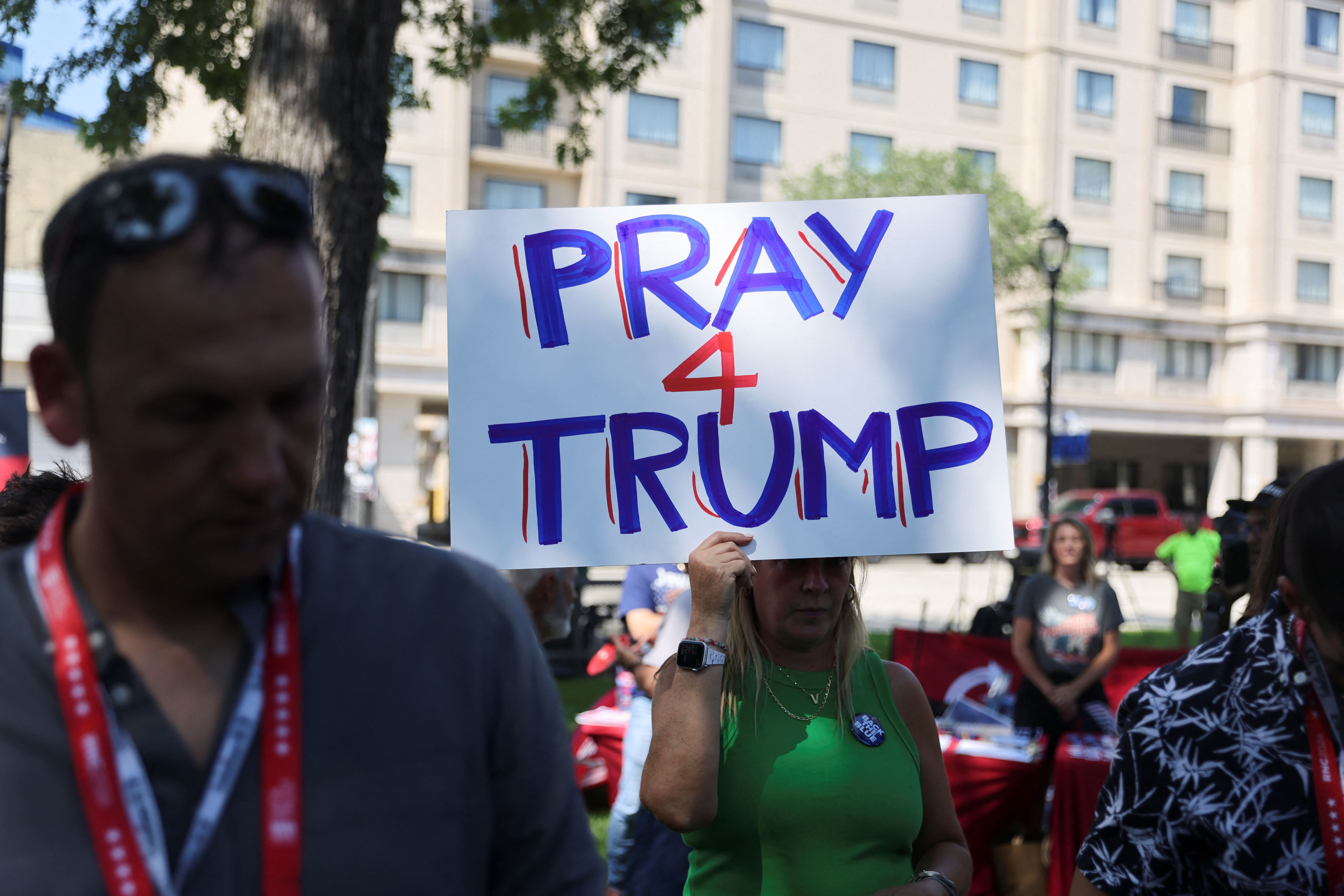 A supporter of former U.S. President Donald Trump holds a placard during a prayer vigil hosted by Turning Point Action near the venue for the Republican National Convention (RNC), at Zeidler Union Square in Milwaukee, Wisconsin, U.S., July 14, 2024 the day after shots were fired at a Trump rally and he was injured in Butler, Pennsylvania. REUTERS/Jeenah Moon