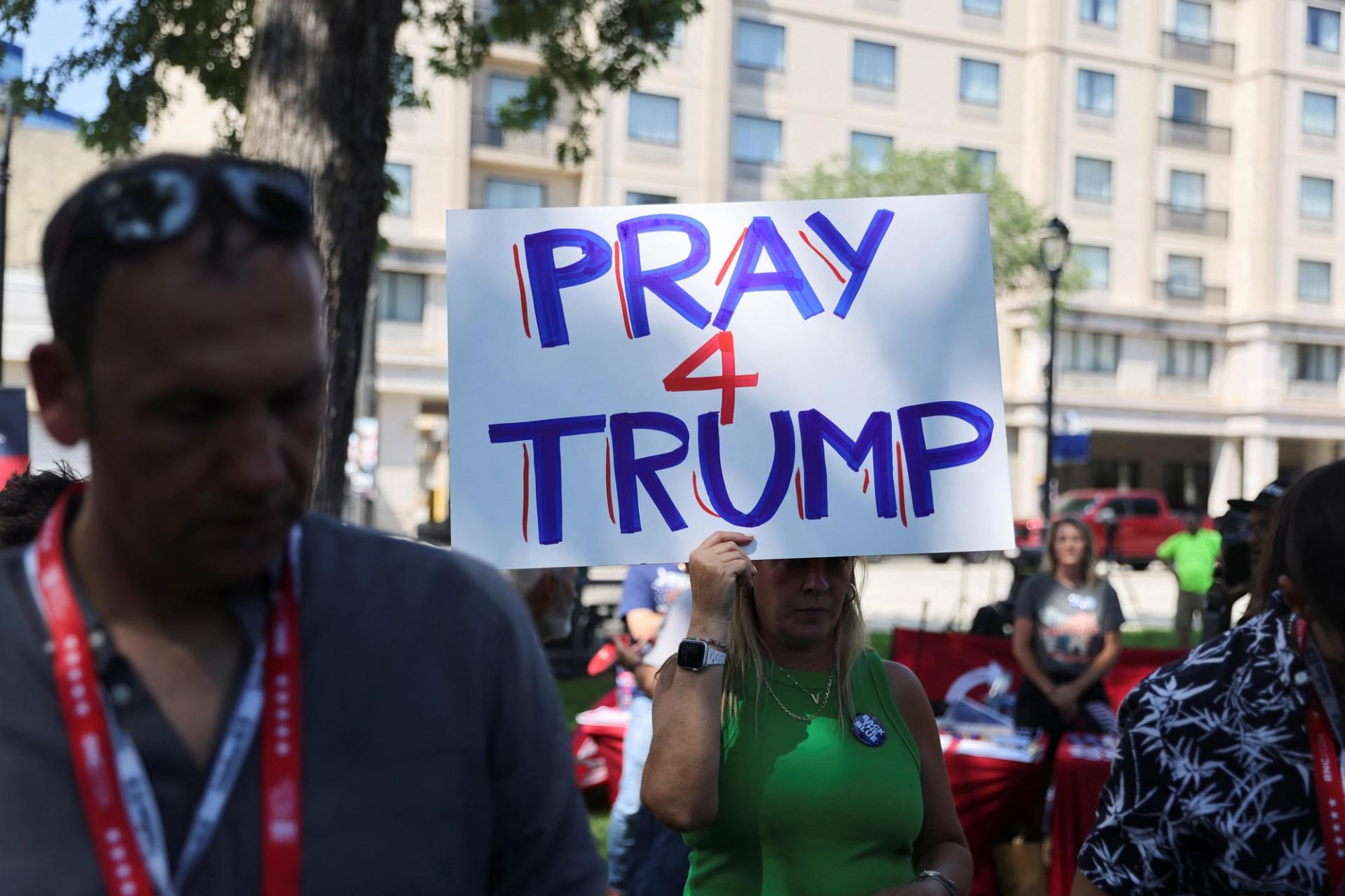 A supporter of former U.S. President Donald Trump holds a placard during a prayer vigil hosted by Turning Point Action near the venue for the Republican National Convention (RNC), at Zeidler Union Square in Milwaukee, Wisconsin, U.S., July 14, 2024 the day after shots were fired at a Trump rally and he was injured in Butler, Pennsylvania. REUTERS/Jeenah Moon