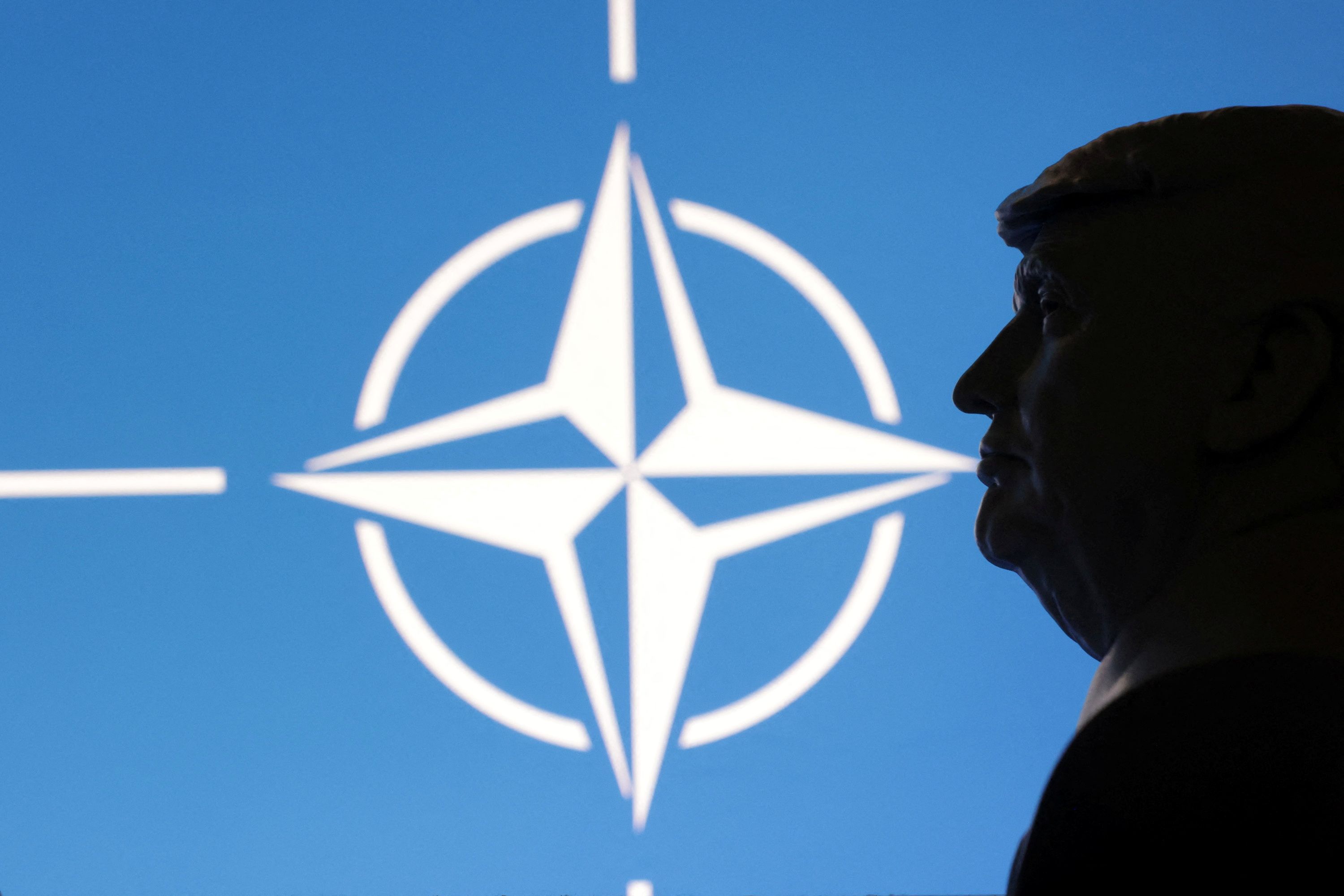 Trump in front of the NATO logo.