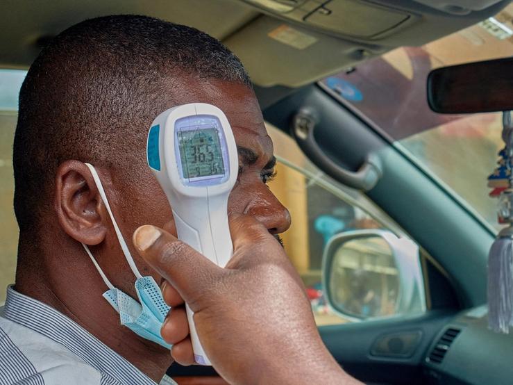 A motorist has his temperature taken by a medical worker at a screening checkpoint.