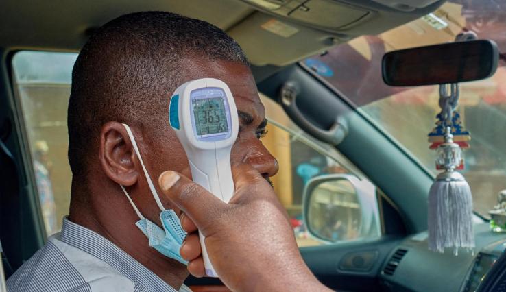 A motorist has his temperature taken by a medical worker at a screening checkpoint.