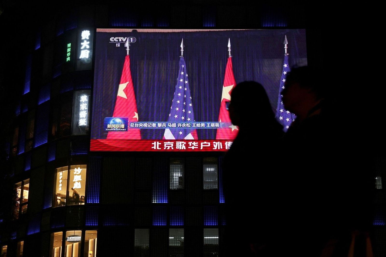 Screen shows news footage of meeting between Xi and Trump, outside a shopping mall in Beijing