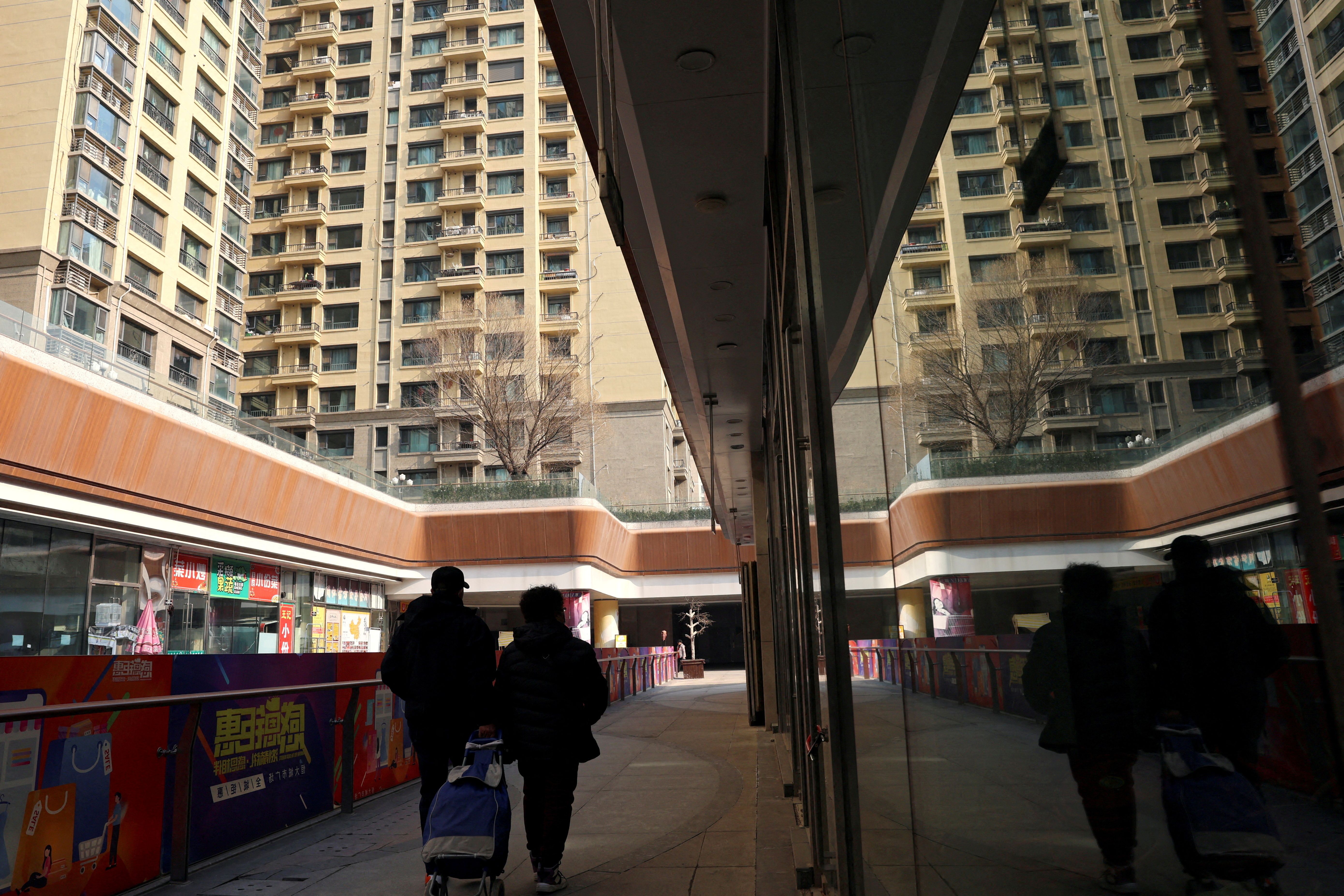 People walk past residential buildings next to the Evergrande City Plaza in Beijing
