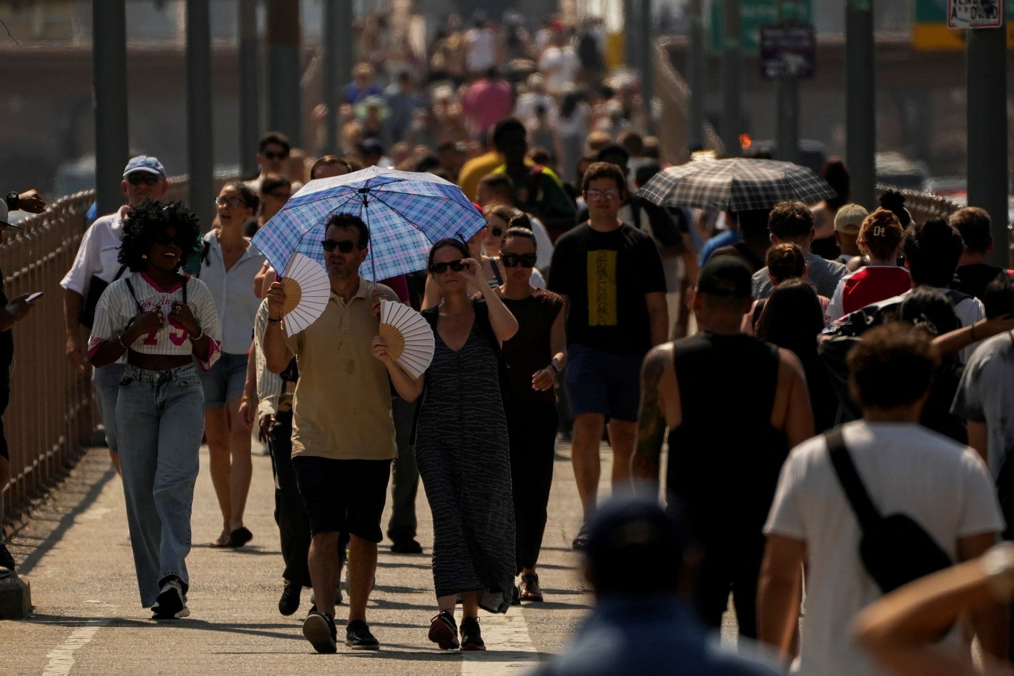 Crowds walk across a bridge in New York City during a heat wave
