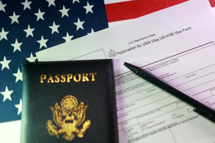 A US flag, a passport and a US H-1B Visa application form are seen in this illustration.