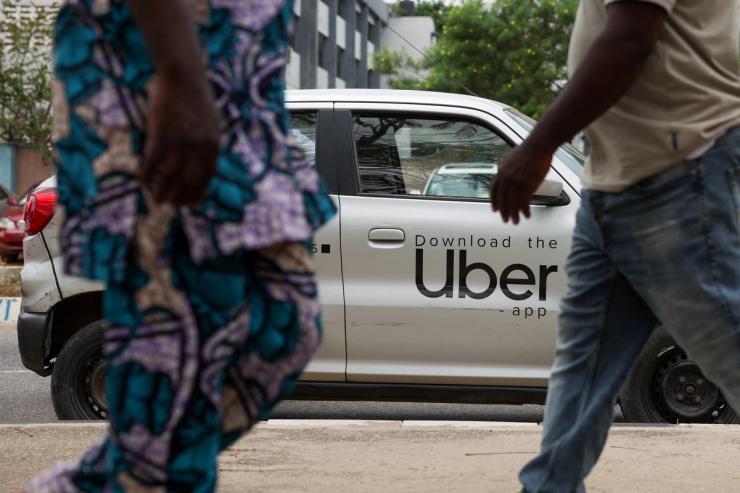 People walk past an Uber car in Lagos.