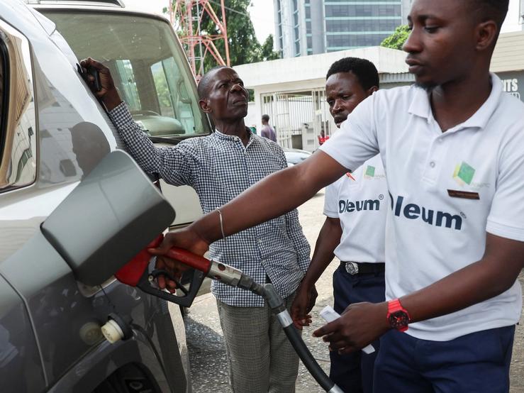 A motorist looks on as a fuel attendant fills his car on the forecourt of a Nigerian National Petroleum Company (NNPC) filling station.