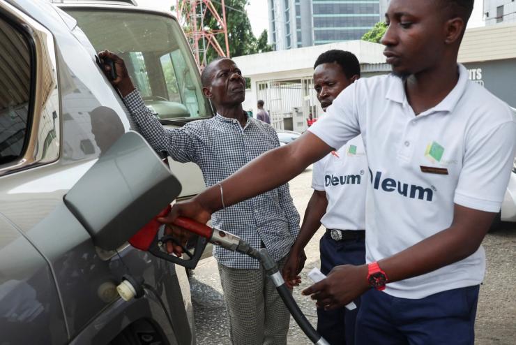 A motorist looks on as a fuel attendant fills his car on the forecourt of a Nigerian National Petroleum Company (NNPC) filling station.
