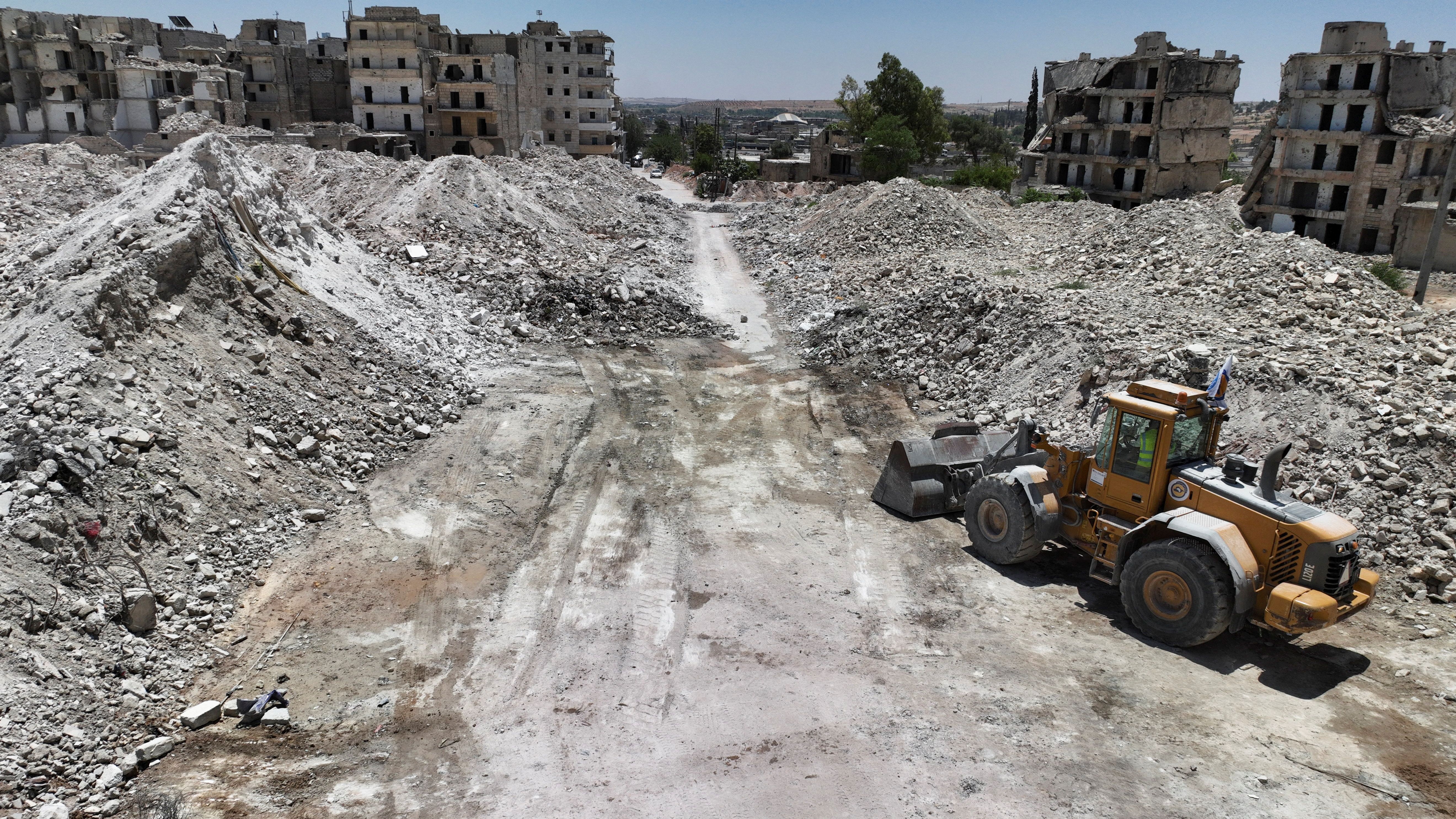 A drone view shows destroyed buildings and massive piles of rubble, as a bulldozer stands nearby, in Aleppo, Syria.