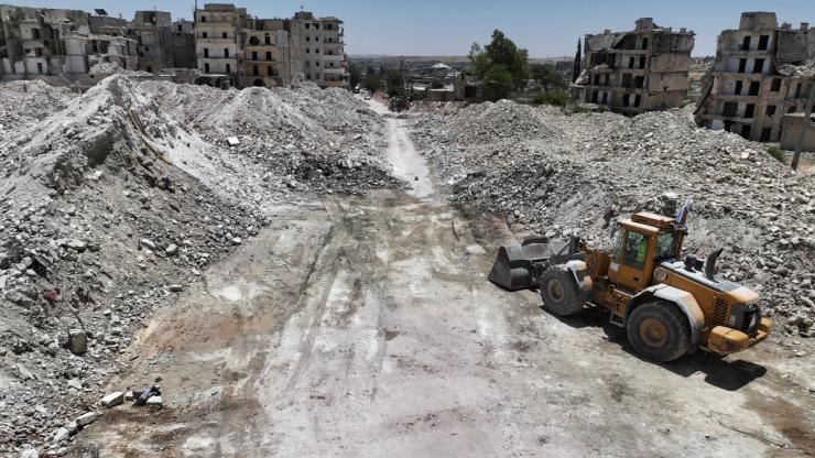 A drone view shows destroyed buildings and massive piles of rubble, as a bulldozer stands nearby, in Aleppo, Syria.