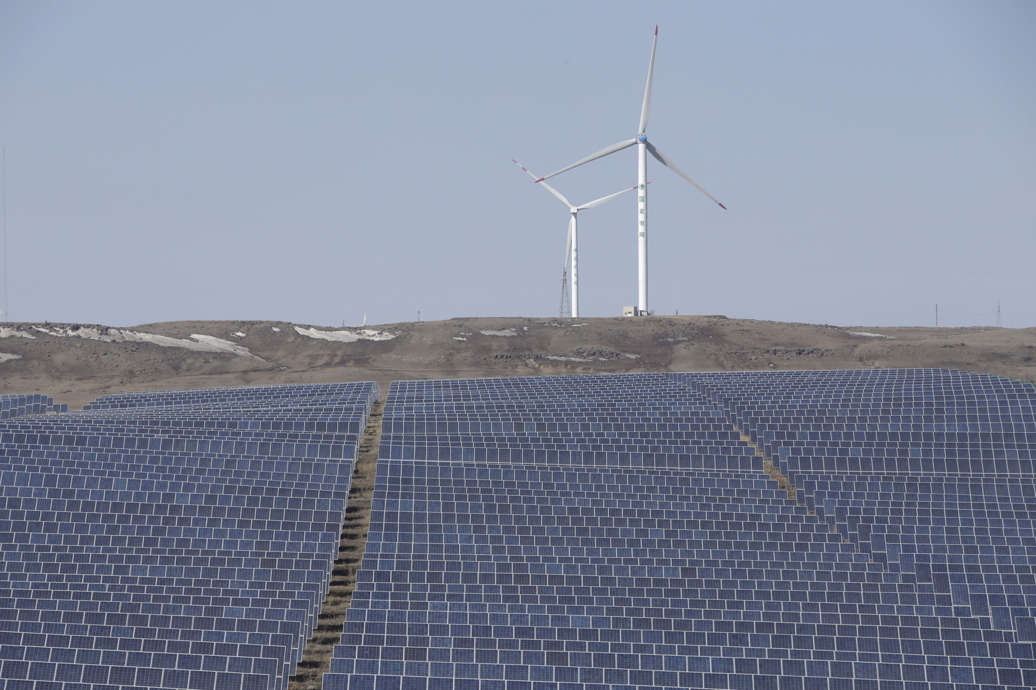 Wind turbines and solar panels are seen at a wind and solar energy storage and transmission power station in China.