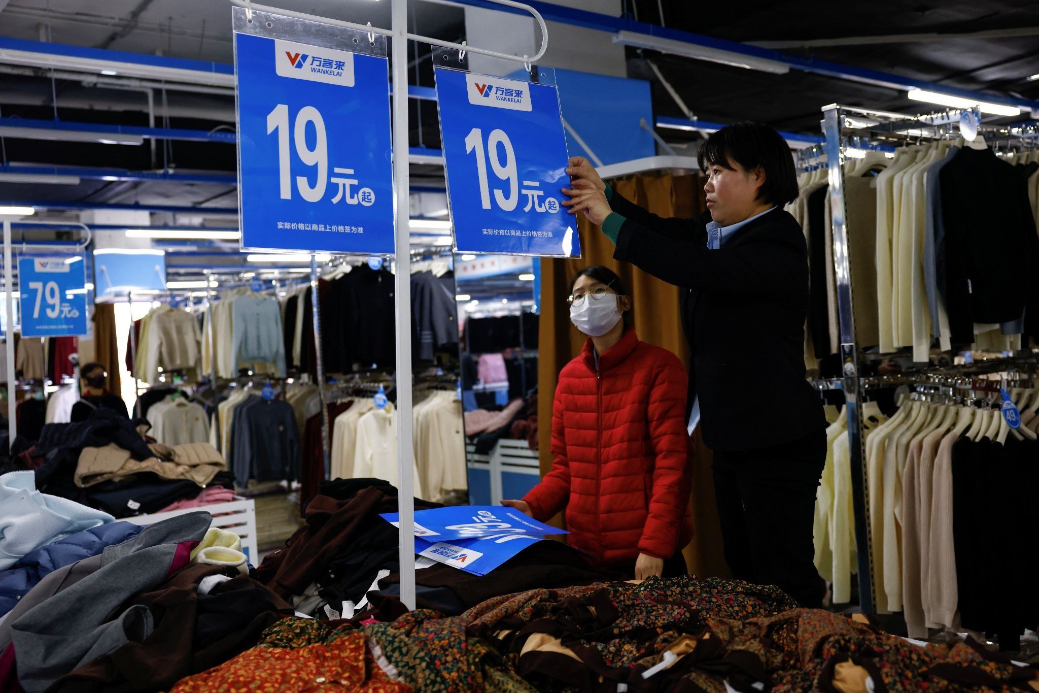 A department store employee changes price signs