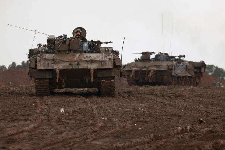 Israeli armored personnel carriers maneuver at Israel’s border with Gaza in southern Israel, December 13, 2023.