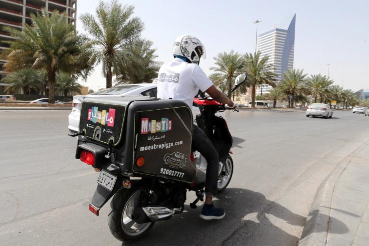 A delivery man rides his motorbike to deliver food orders for customers in Riyadh in 2020.
