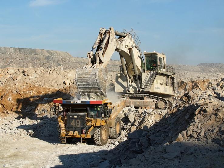 An excavator fills a dumper truck with ore at a mine in DR Congo.