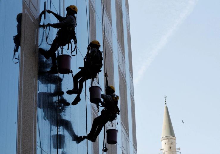 Workers clean the glass facade of a building in Jeddah, Saudi Arabia. July 13, 2022.