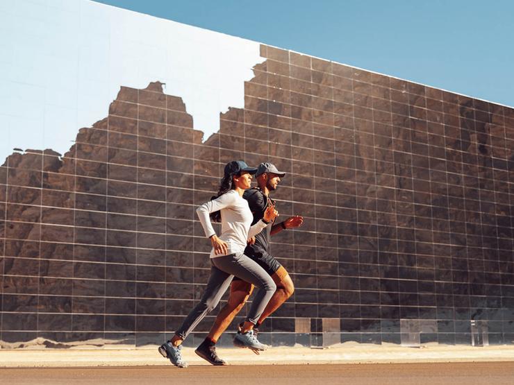 A man and a woman run past Maraya (mirrors) Hall in AlUla