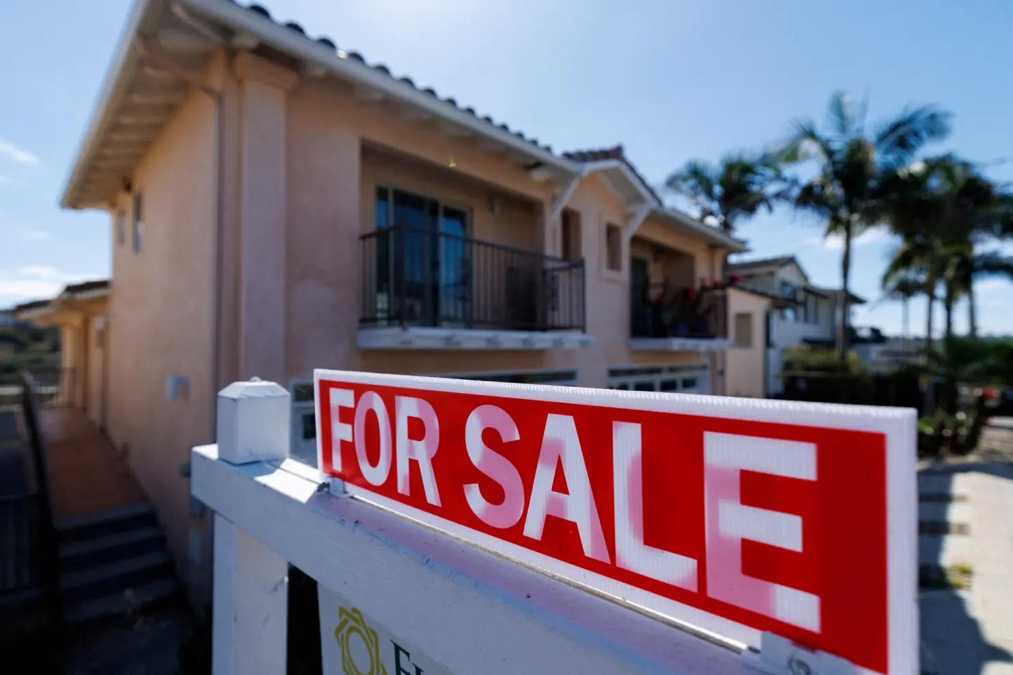 A house showing a for-sale sign in front.