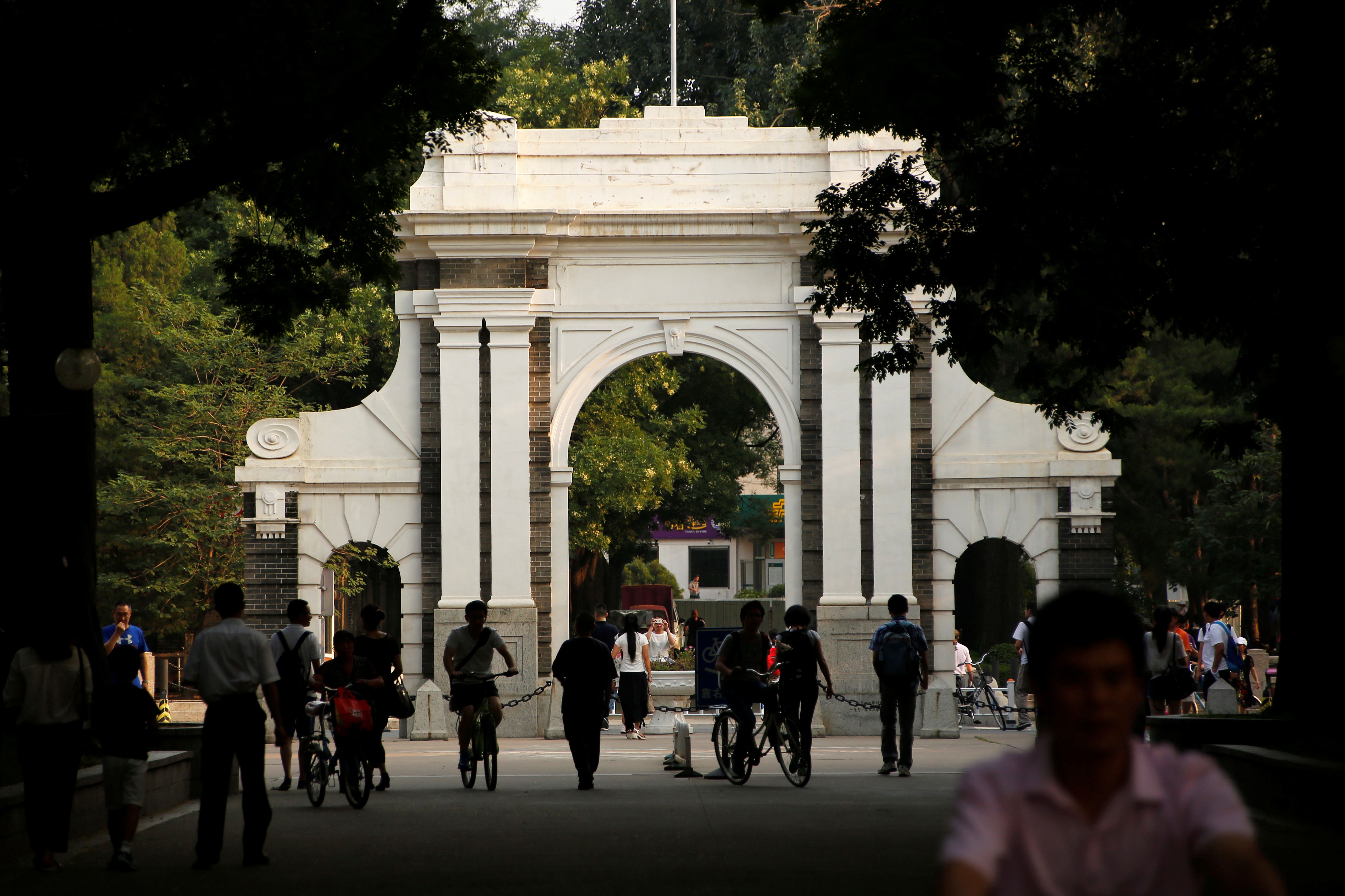 People walk near the gate of Tsinghua University in Beijing