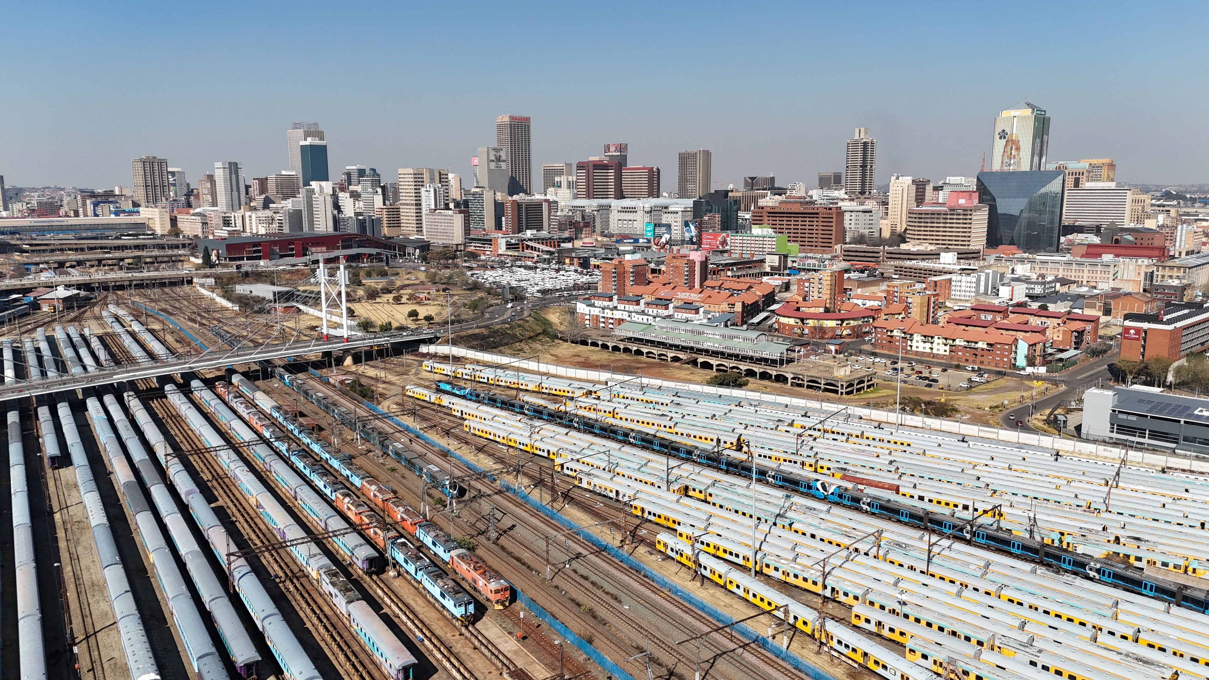 Trains parked beneath the Nelson Mandela Bridge with part of the city of Johannesburg
