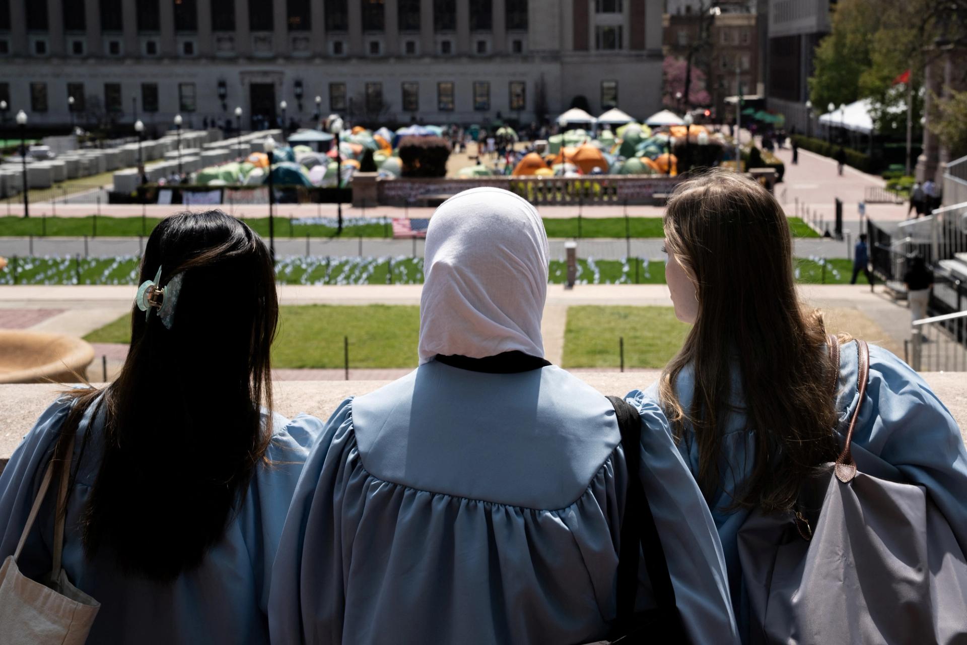 Students in graduation gowns overlook at a protest encampment that has been erected in support of Palestinians at the Columbia University campus on April 28, 2024.