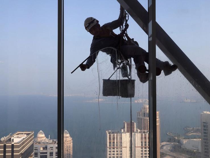 A worker cleans a window of a residential building in Doha, Qatar, August 25, 2024.