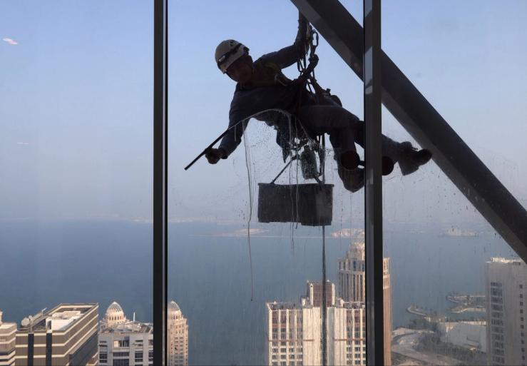 A worker cleans a window of a residential building in Doha, Qatar, August 25, 2024.