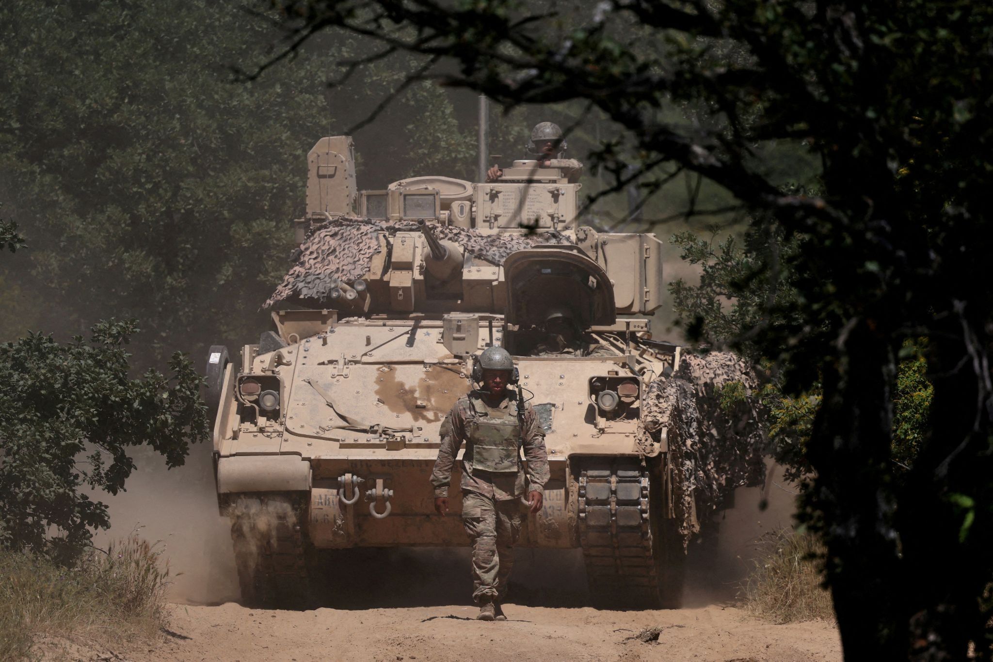 A US soldier walks in front of an armoured vehicle. 