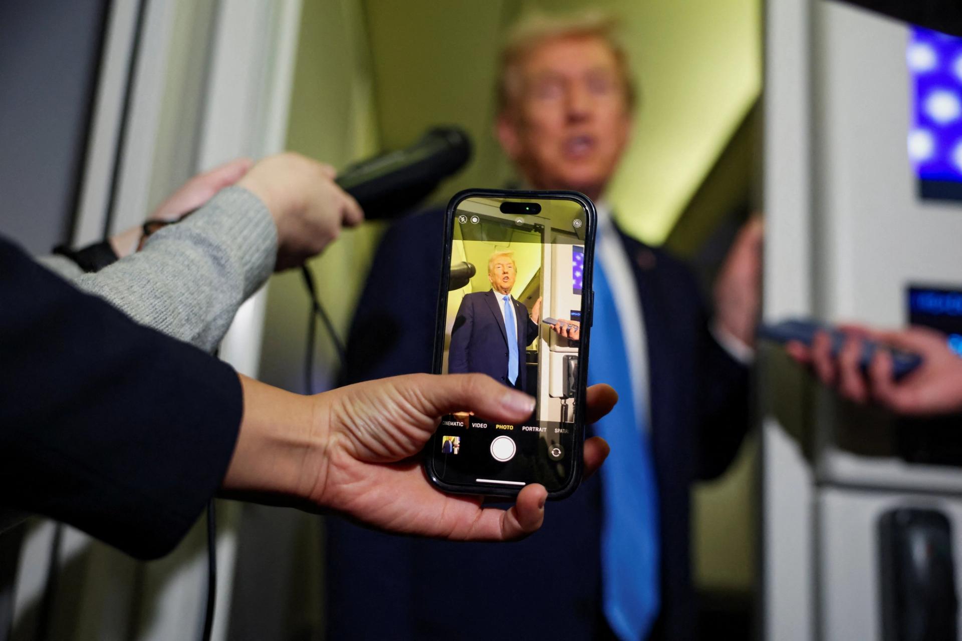 A media member records Trump on their phone