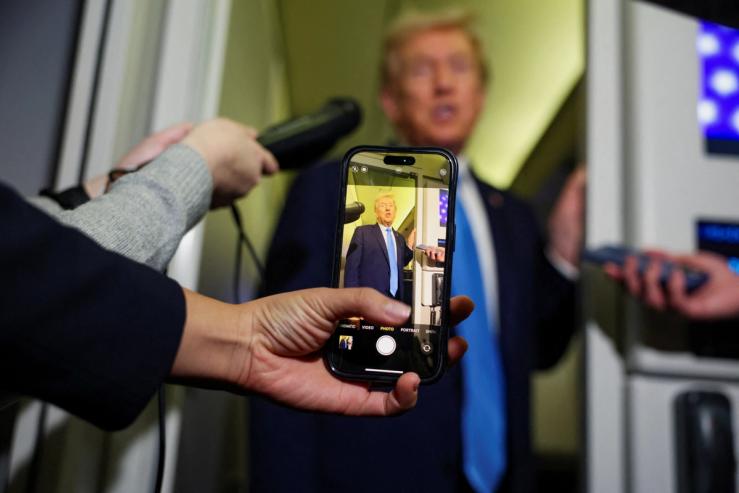 A media member records Trump on their phone